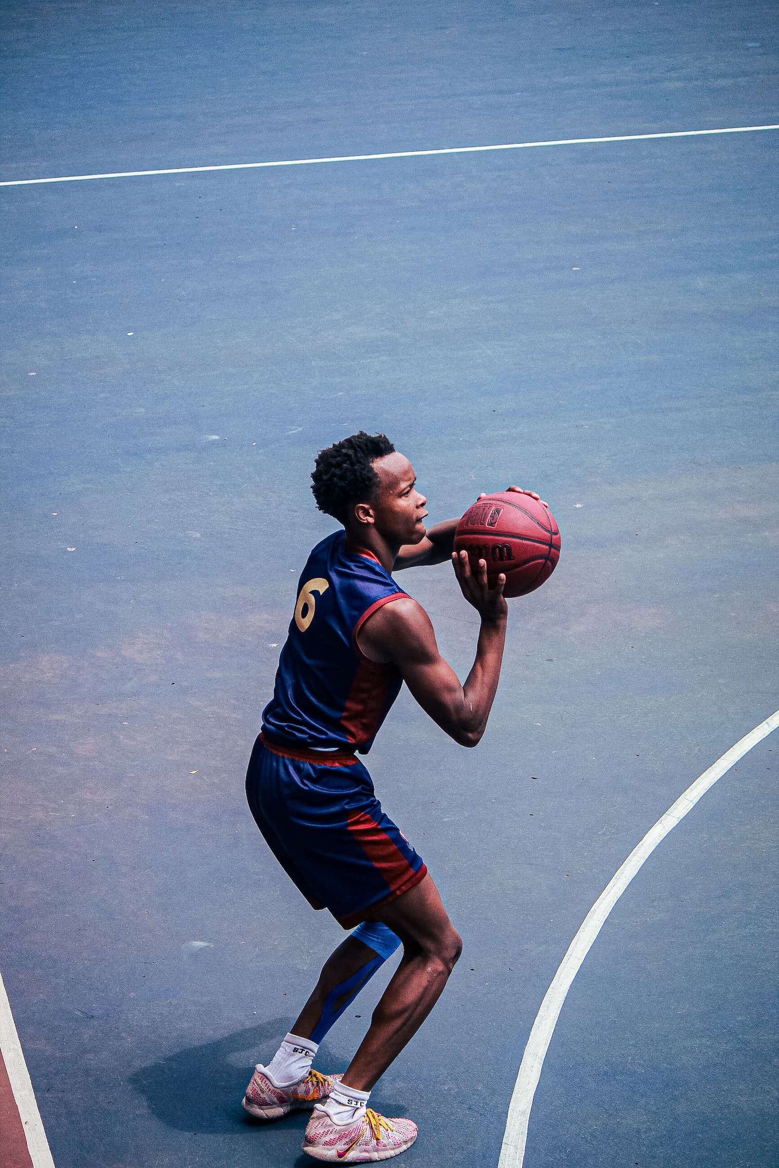 Basketball player mid-shot under floodlights